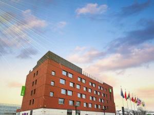 ein rotes Backsteingebäude mit Flaggen davor in der Unterkunft ibis Styles Warszawa Airport in Warschau