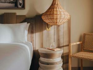 Hyde Hotel Ibiza Beach Resort by ACCOR في كالا يونغا: غرفة نوم بسرير ومصباح وكرسي