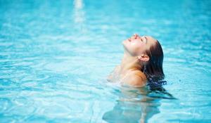 a woman laying in the water in a pool at White House Safari Cottage in Udawalawe