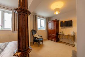 a bedroom with a bed and a chair and a television at The Hawk & Buckle Inn in Llannefydd