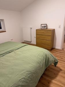een slaapkamer met een groen bed en een houten dressoir bij Leni Vacation Rental in Hattert