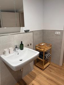 een badkamer met een witte wastafel en een spiegel bij Leni Vacation Rental in Hattert