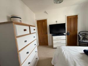 a bedroom with a bed and a dresser with a television at Silsoe Cottage B&B in Silsoe