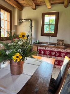 Chalet Valchiavenna في San Cassiano: مطبخ مع طاولة عليها زهور الشمس