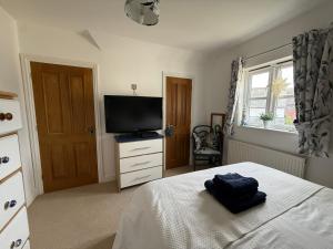a bedroom with a bed and a flat screen tv at Silsoe Cottage B&B in Silsoe