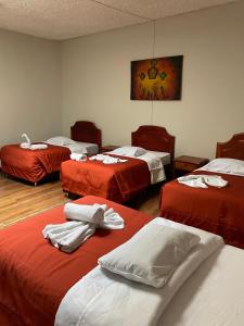 een kamer met drie bedden met rode en witte lakens bij Inkas Hotel Cusco in Cuzco