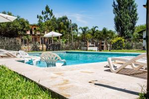 a swimming pool with chairs and an umbrella at Cabañas Las Victorias in Colón +7 photos