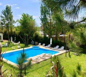 a swimming pool in a yard with chairs and trees at Cabañas Las Victorias in Colón