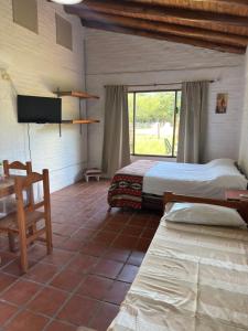 a bedroom with two beds and a table and a window at Cabañas Las Victorias in Colón