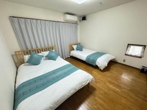 a bedroom with two beds and a window and wooden floors at MARU KIX House in Izumi-Sano +41 photos