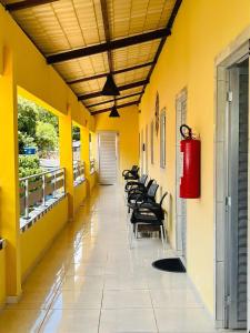 Eine Stuhlreihe in einem Flur mit gelben Wänden in der Unterkunft Fonte dos Corais - Suíte Brisa da Tarde in Maragogi