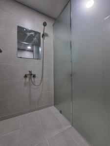 a bathroom with a shower with a television on the wall at Halla Livingtel in Goyang