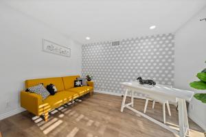 ein Wohnzimmer mit einem gelben Sofa und einem Tisch in der Unterkunft Marbella Lane Modern Home w Private Backyard in La Habra