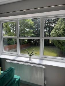 Una sala de estar con tres ventanas y un sofá verde en Elegant Retreat 6 Mins Drive from Ferry With Free Parking, en Dover