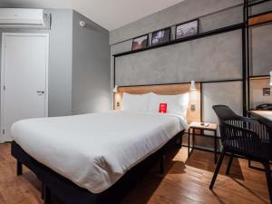 拉夫拉斯ibis Lavras的卧室里有一张白色的大床和一把椅子