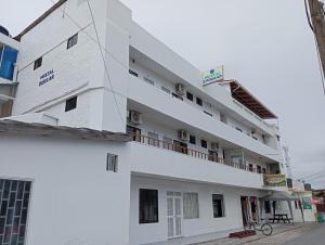 a white building with a balcony on the side at Hostal Insular in Puerto Villamil