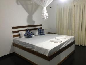 a bedroom with a large bed with two towels on it at White House Safari Cottage in Udawalawe