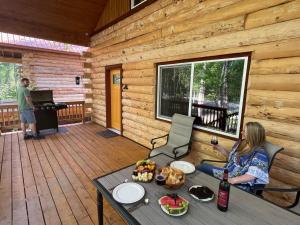 a woman sitting on the porch of a cabin at Riverfront, Authentic, Luxury Log Cabin-Bull Moose in Wasilla