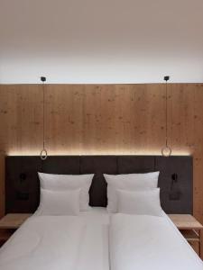 NEW OPENING LA TRUGA Suite Apartments في سيلفا دي فال جاردينا: غرفة نوم بسريرين مع شراشف بيضاء واضاءات