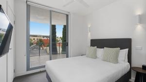 a bedroom with a white bed and a large window at District Apartments Fitzroy in Melbourne