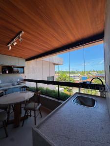a kitchen with a table and a large window at Flat Garden Frances in Marechal Deodoro