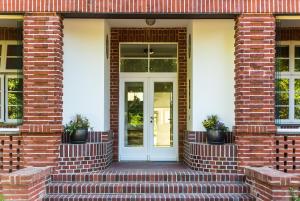 a brick house with a white door with potted plants at Villa Höger in Boltenhagen