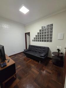 a living room with a black leather couch and a television at Casa do Mateus no bairro Pilar in Ouro Preto