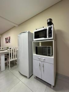 Un microondas encima de un refrigerador en una cocina. en Casa Familiar - Próximo ao Aeroporto - WI-FI - Garagem Privativa GEM17, en Joinville