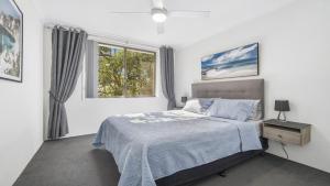 a white bedroom with a bed and a window at Flynns Beach Seascape in Port Macquarie