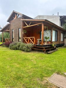 een houten huis met een veranda en een tuin bij Cabañas en Concordia in Concordia