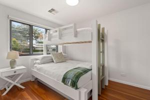a white bedroom with a bunk bed and a window at Coast Bliss on Currambene in Huskisson