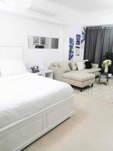 a white bedroom with a bed and a couch at aeon condon studio unit in Davao City