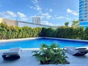 a swimming pool with two lounge chairs next to a building at aeon condon studio unit in Davao City