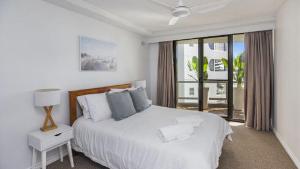 a white bedroom with a bed and a window at Beachside Bliss in Port Macquarie +5 photos