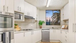 a white kitchen with white cabinets and a window at Beachside Bliss in Port Macquarie