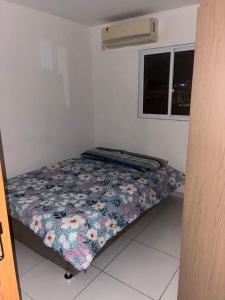 Bett in einem Zimmer mit Blumenbettdecke in der Unterkunft Apartamento Mobiliado! in João Pessoa
