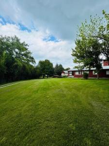 Rocco Housse في لوس هورنيلوس: حقل أخضر واسع به مبنى أحمر وأشجار