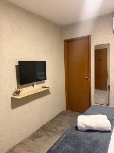 a room with a tv on a wall with a bed at Pousada Arena 165 in Murici