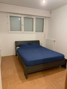 una camera da letto con un letto con lenzuola blu e due finestre di Apt a Rezé