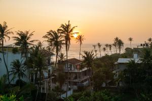 a view of the ocean and palm trees at sunset at Mountain Relax Inn in Weligama
