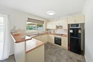 a kitchen with white cabinets and a black refrigerator at Bellbird Willow Hunter Escape by Nature & Winery in Bellbird