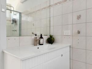 ein weißes Badezimmer mit Waschbecken und Spiegel in der Unterkunft Blue Lotus Riverfront Villas Nelligen in Nelligen + 26 Fotos