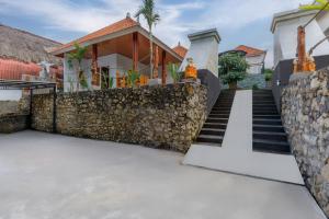 een huis met een stenen muur en een trap bij Memela Bungalow in Nusa Penida