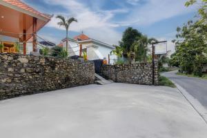 a stone wall next to a street with a building at Memela Bungalow in Nusa Penida