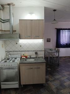a kitchen with a stove and a sink and a table at Alojamiento Entero con Excelente Ubicación in Morón