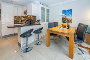 a kitchen with a wooden table and black chairs at Godewind App 5 in Westerland