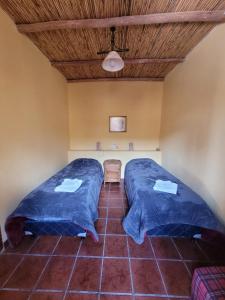 two beds in a room with blue sheets at Ñawpa Wasi in Humahuaca