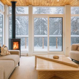 a living room with a fireplace and snow covered trees at Le Belvédère - Retraite scandivane in Saint Adolphe D'Howard