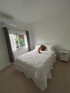 a white bed in a bedroom with a window at Agape Suites-Room 4- 1st Floor in Soufrière
