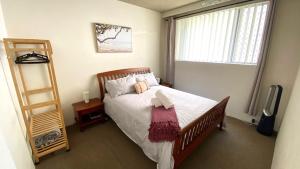 a bedroom with a bed with white sheets and a window at Central Wollongong Apartment - 2 bedrooms in Wollongong